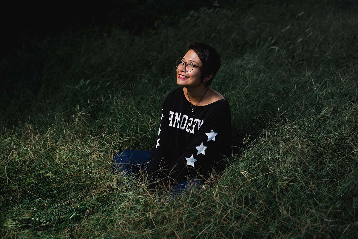 person woman sitting on grass smiling and looking up during nighttime people