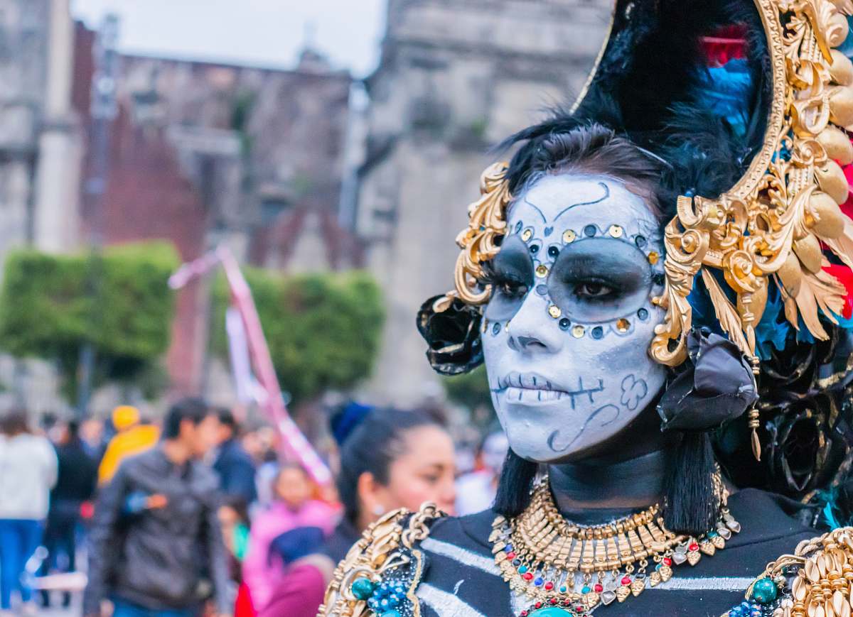 person woman wearing gold-colored accessories and face paint crowd