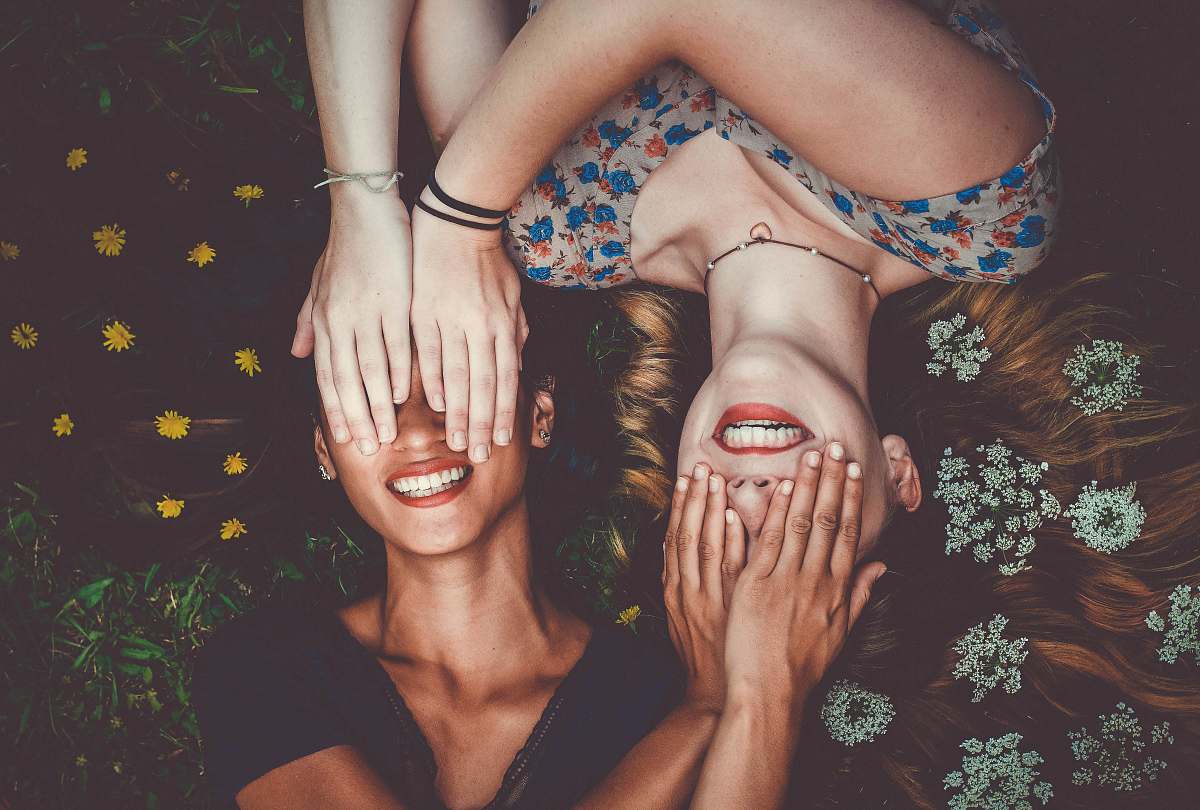 woman man and woman smiling while laying on lawn field friend