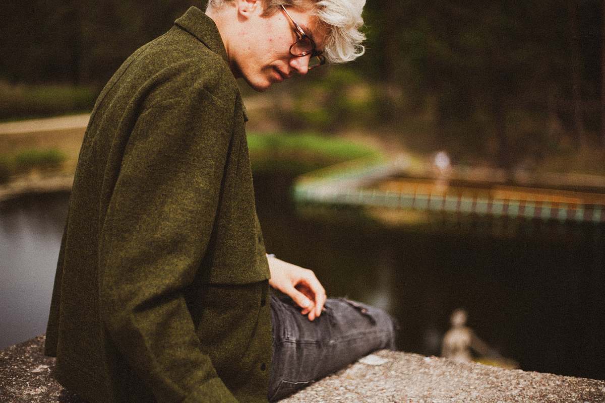 clothing man wearing green jacket sitting on bench wood