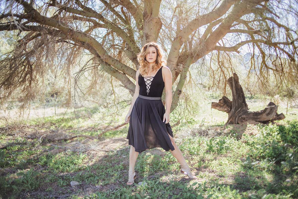 clothing woman in black dress standing in front of tree evening dress