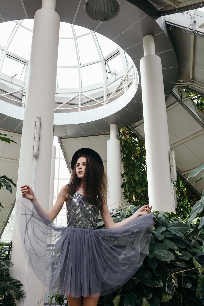 clothing woman in gray sleeveless dress wearing black hat under white dome fashion