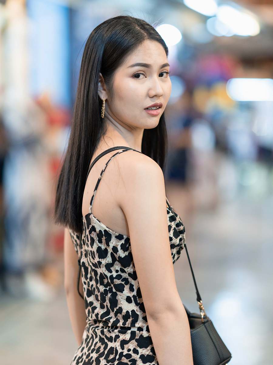 clothing woman standing with black and white leopard dress and crossbody bag evening dress