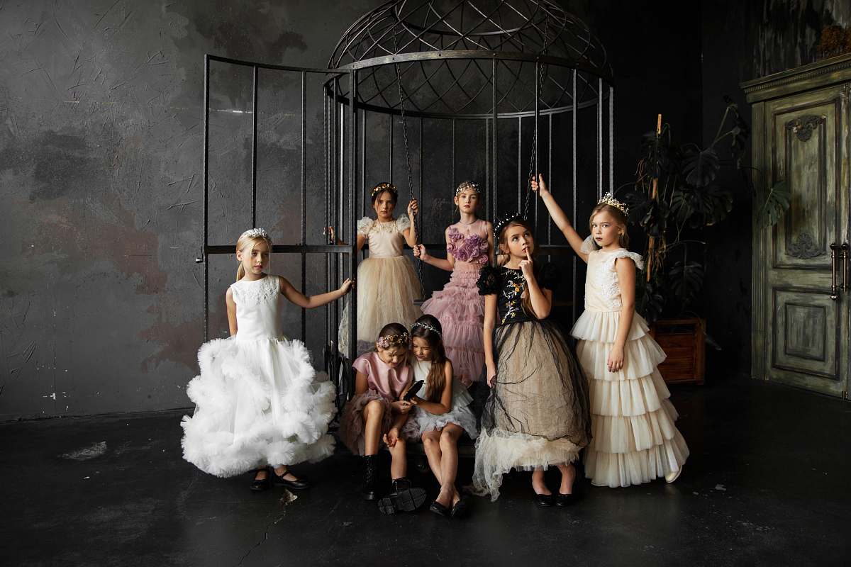 fashion girls wearing dresses standing and sitting inside dark room apparel