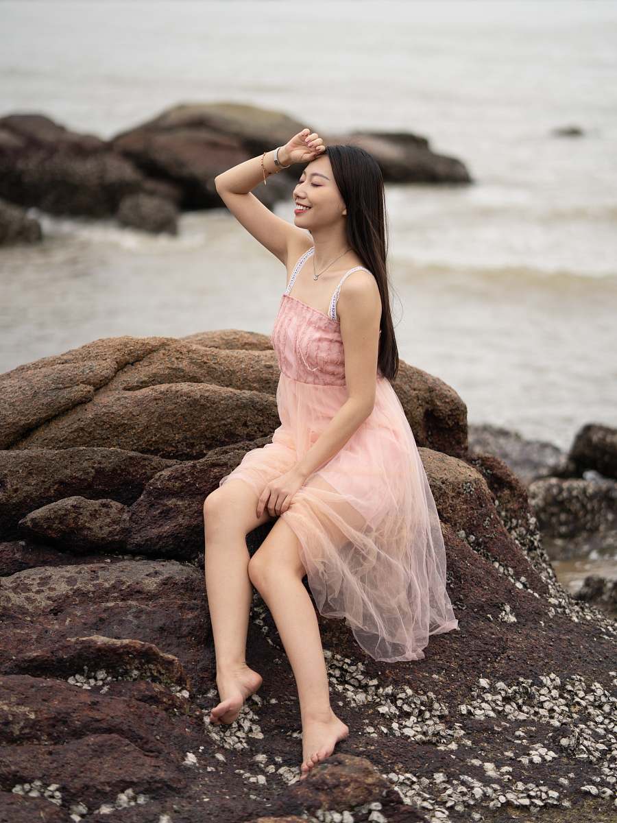 apparel woman in pink dress sitting on seaside rocks evening dress