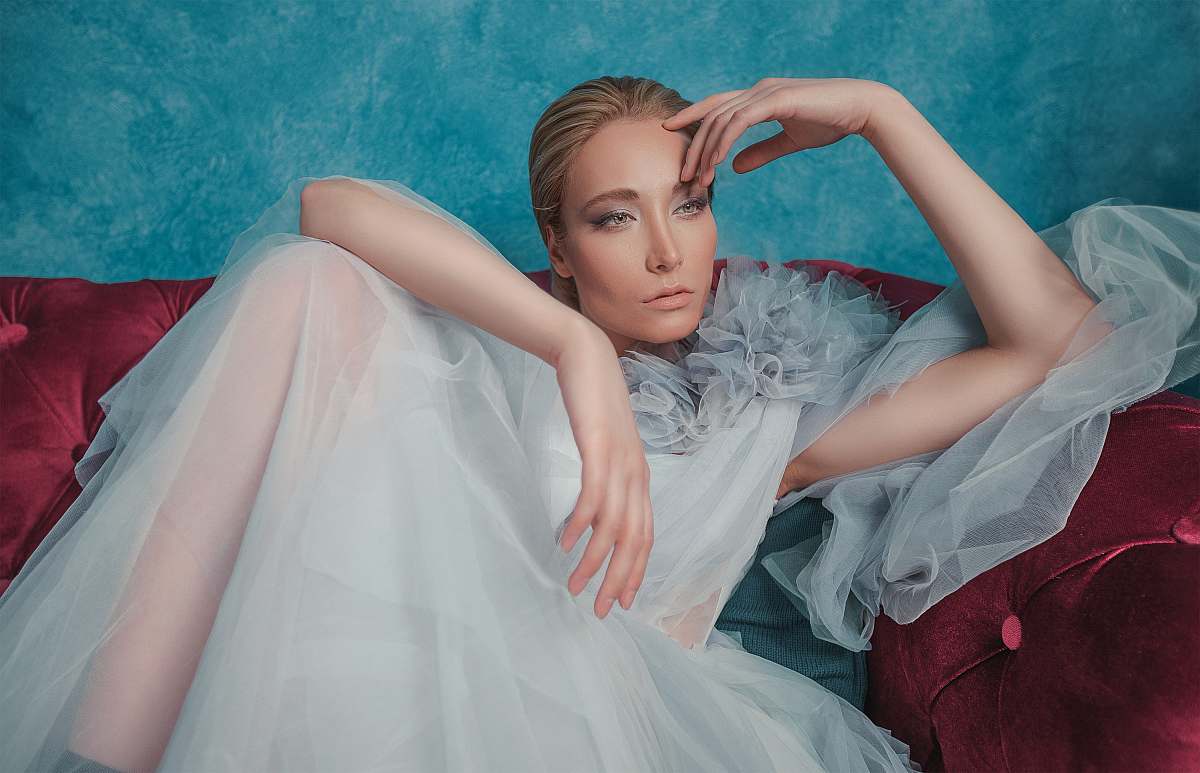 apparel woman in white dress sitting on red sofa gown