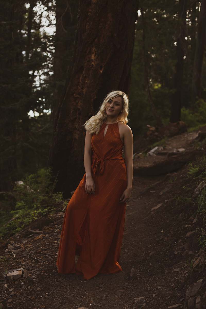apparel woman standing on dirt path near trees robe