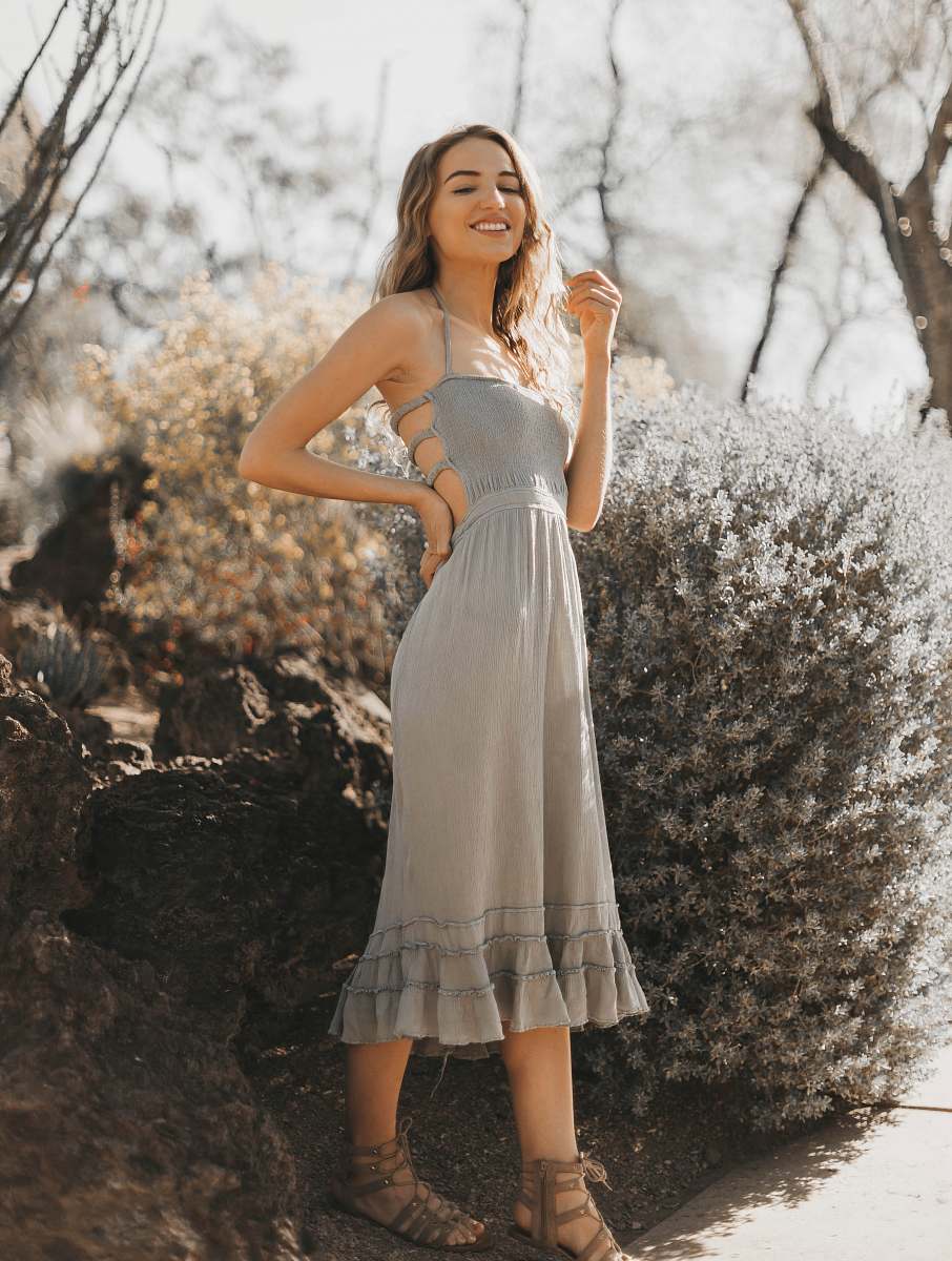apparel woman wearing grey halter dress standing near bush fashion
