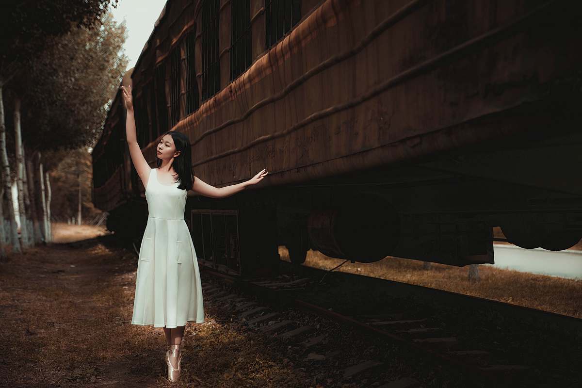 apparel woman wearing white dress dancing beside train fashion