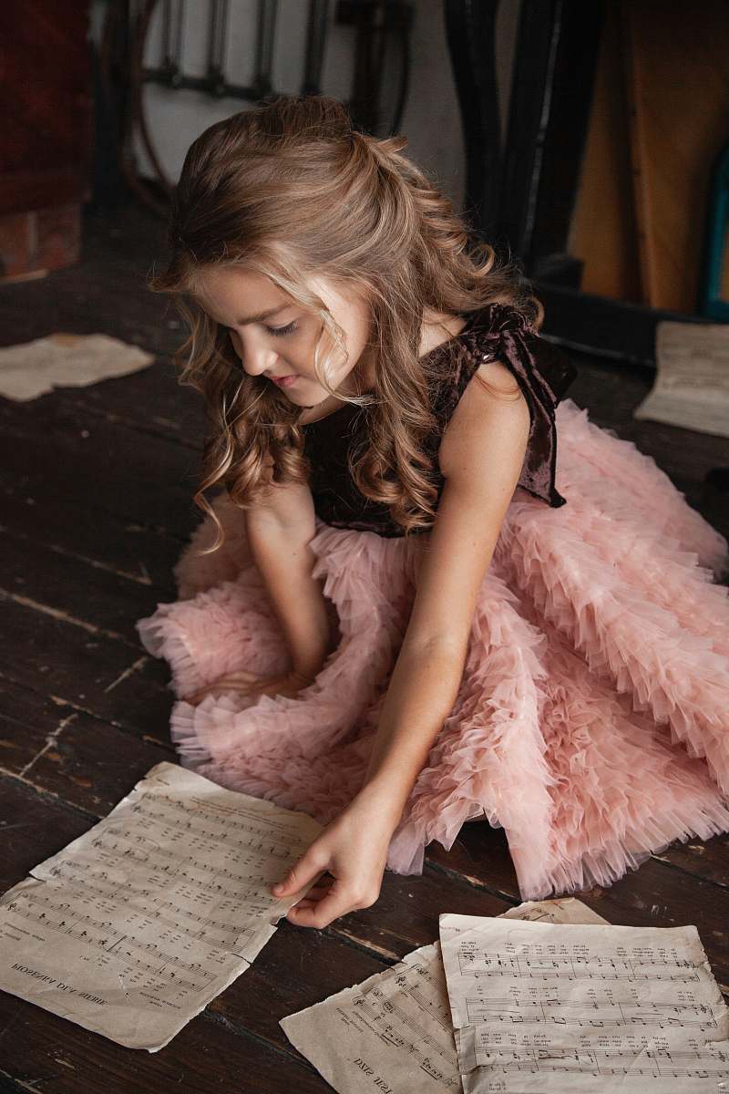 apparel crouching girl wearing pink and black dress holding sheet clothing