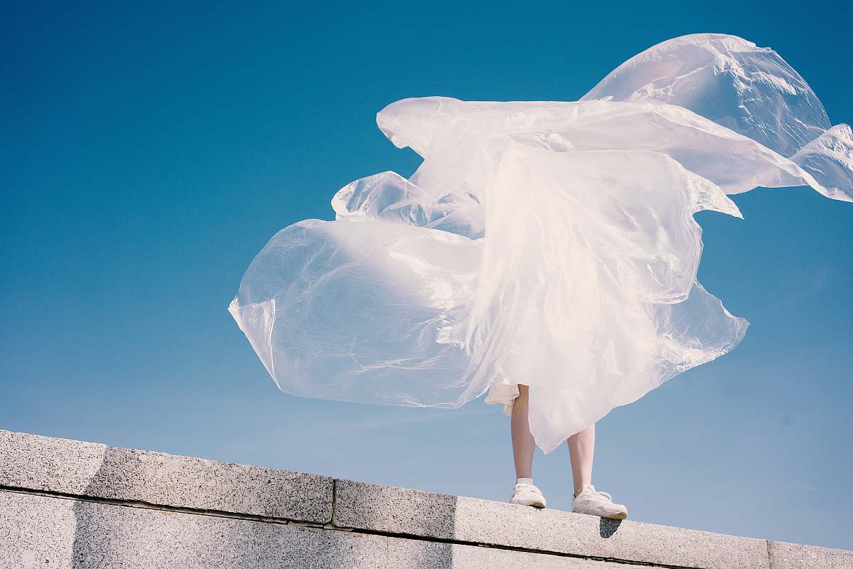 clothing person holding plastic while standing on wall apparel