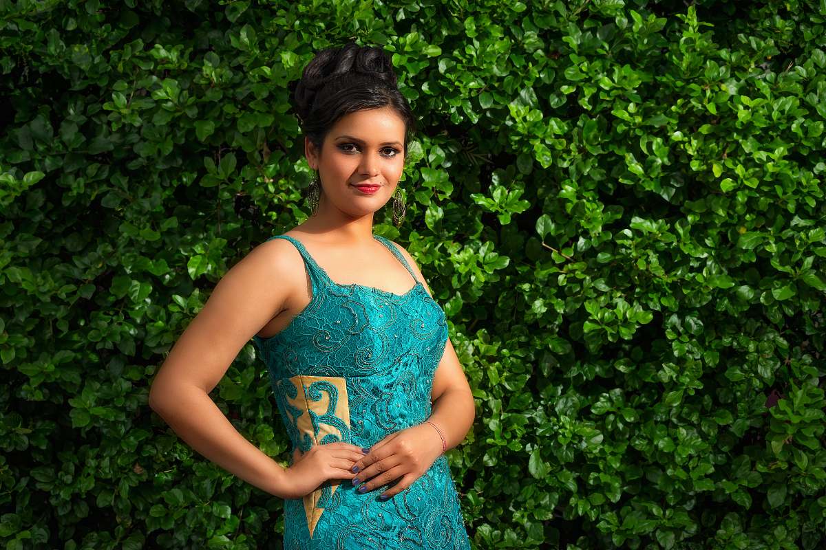 apparel smiling woman wearing green floral spaghetti strap dress standing with left arm akimbo near green leaf plant clothing