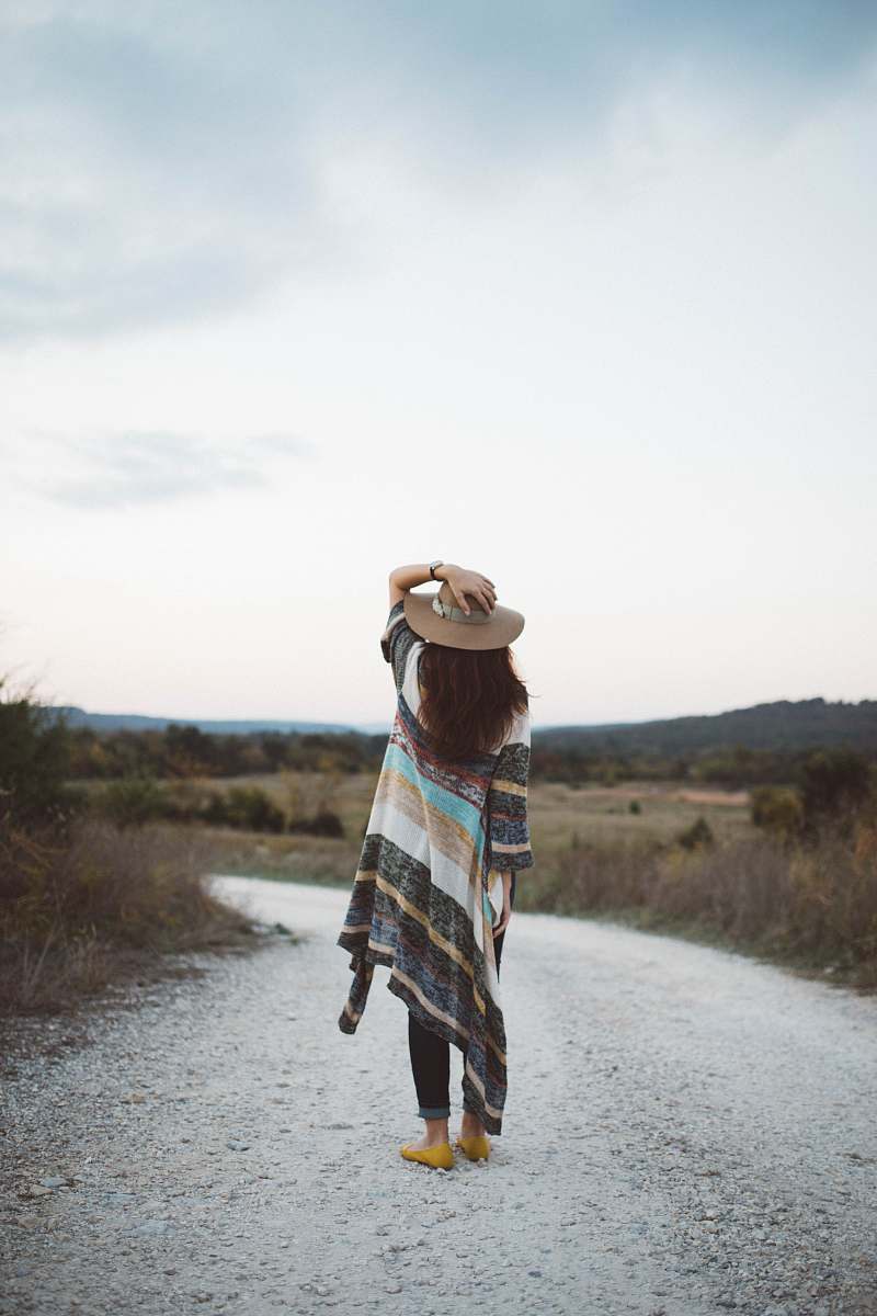 people standing woman holding her hat at the middle of the road during day woman