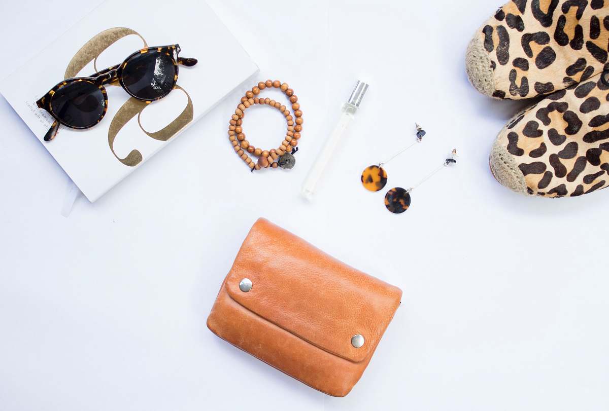 wallet tortoiseshell Clubmaster-style sunglasses near beaded brown necklace handbag