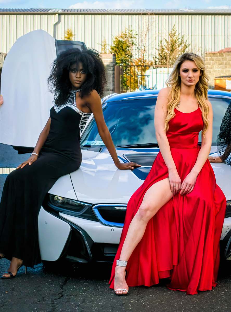 robe two women sitting on white car evening dress