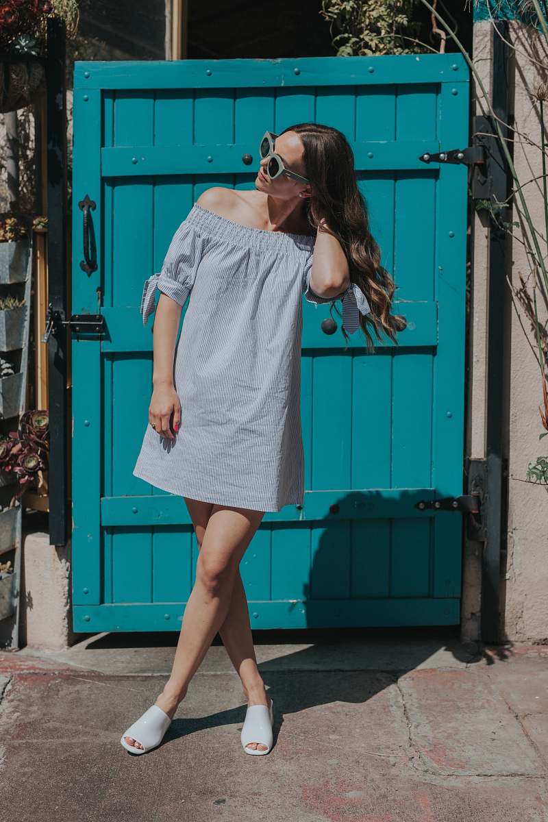 people woman touching her hair standing near teal gate girl