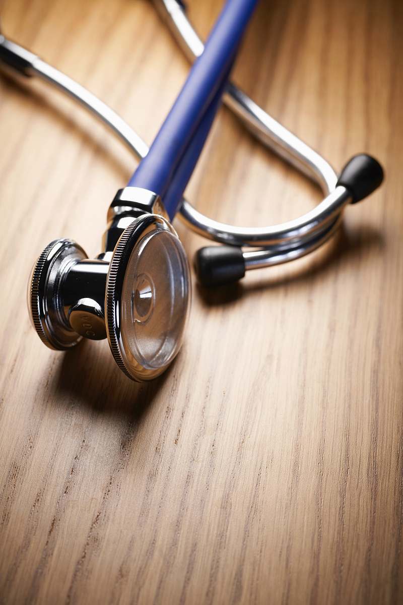 headset shallow focus photo of blue and gray stethoscope on brown wooden table electronics