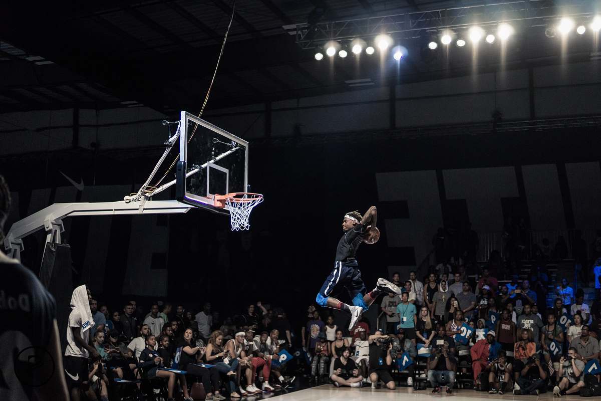 army man jumping and about to shoot the ball in basketball hoop in front of crowd team