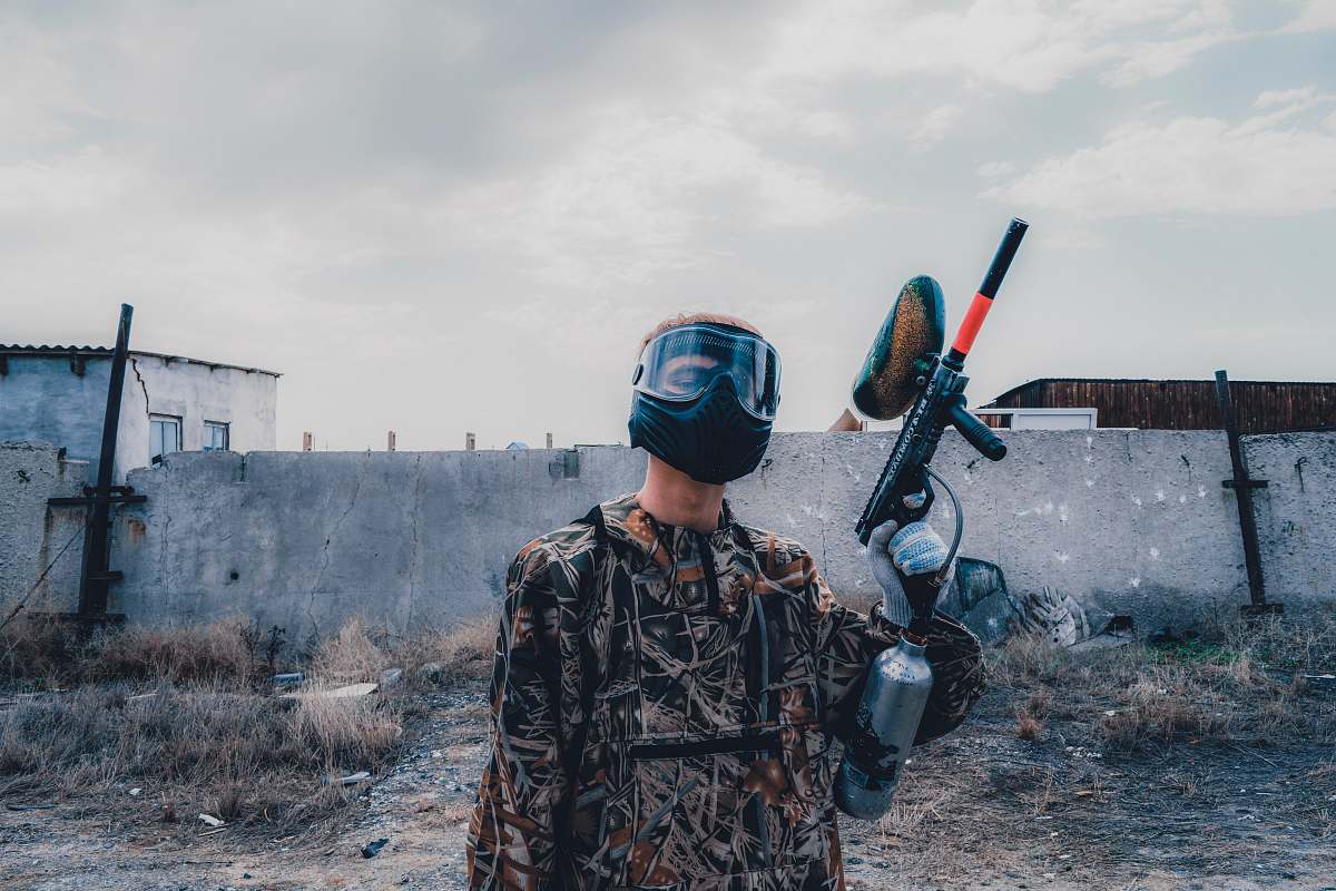 person man wearing mask holding paintball gun during daytime clothing