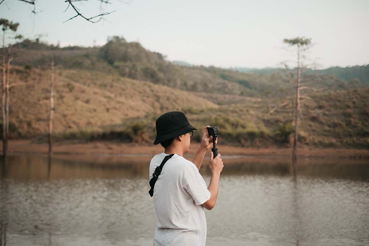 person man wearing white crew-neck shirt taking photo using smartphone photographer