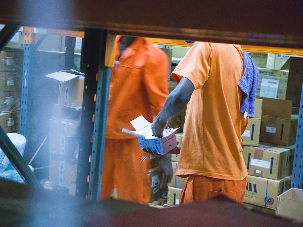 person standing man in orange t-shirt holding white box uganda