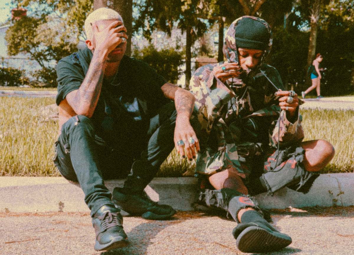 person two men sitting beside road apparel