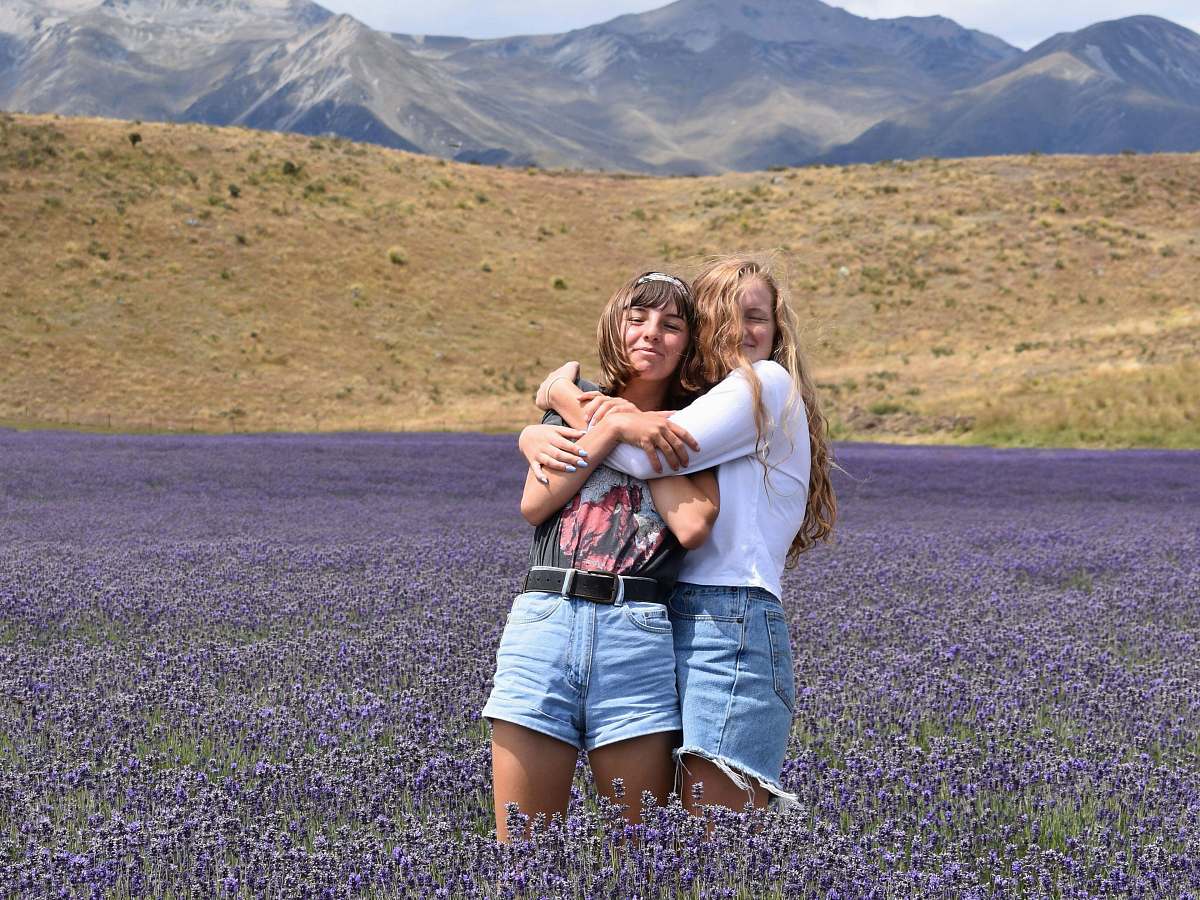 person woman hugging another woman on purple flower field people