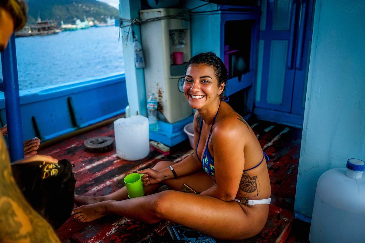 person woman in blue bikini top holding green mug while sitting inside boat people