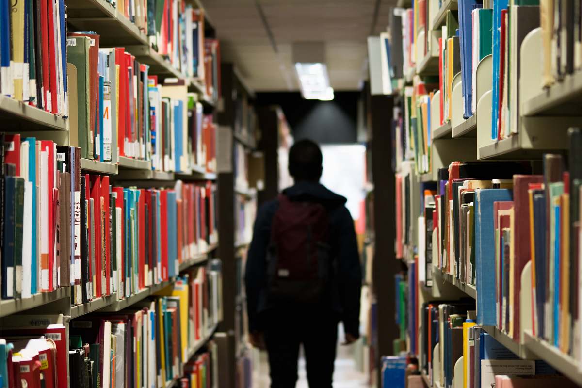 person man with backpack beside a books human