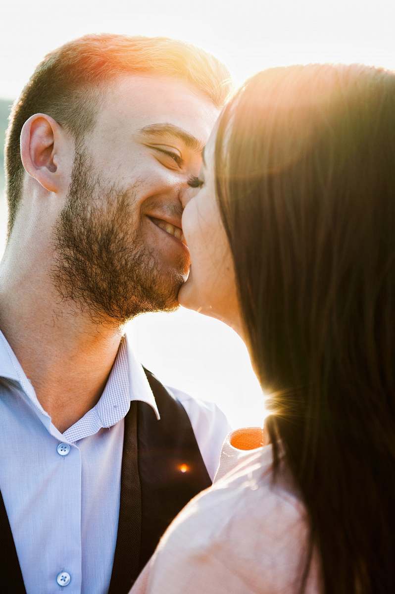 person smiling coupe kissing with sun rays during daytime human