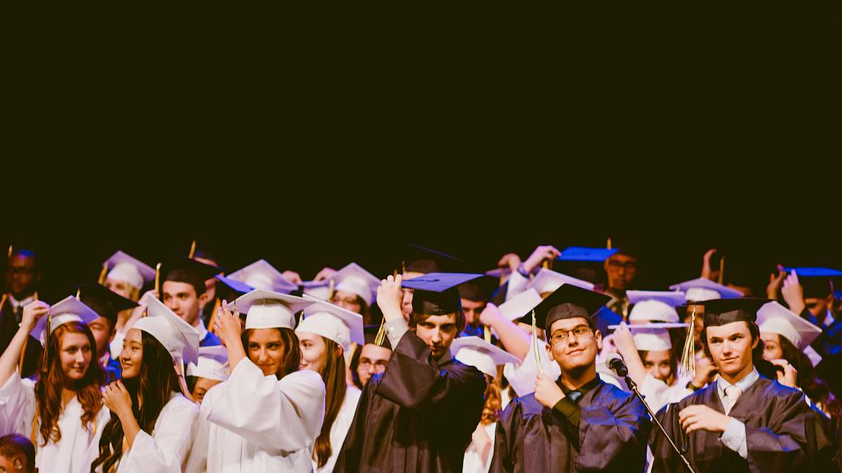 people men and women wearing black and white graduation dress and mortar cap inside building graduation