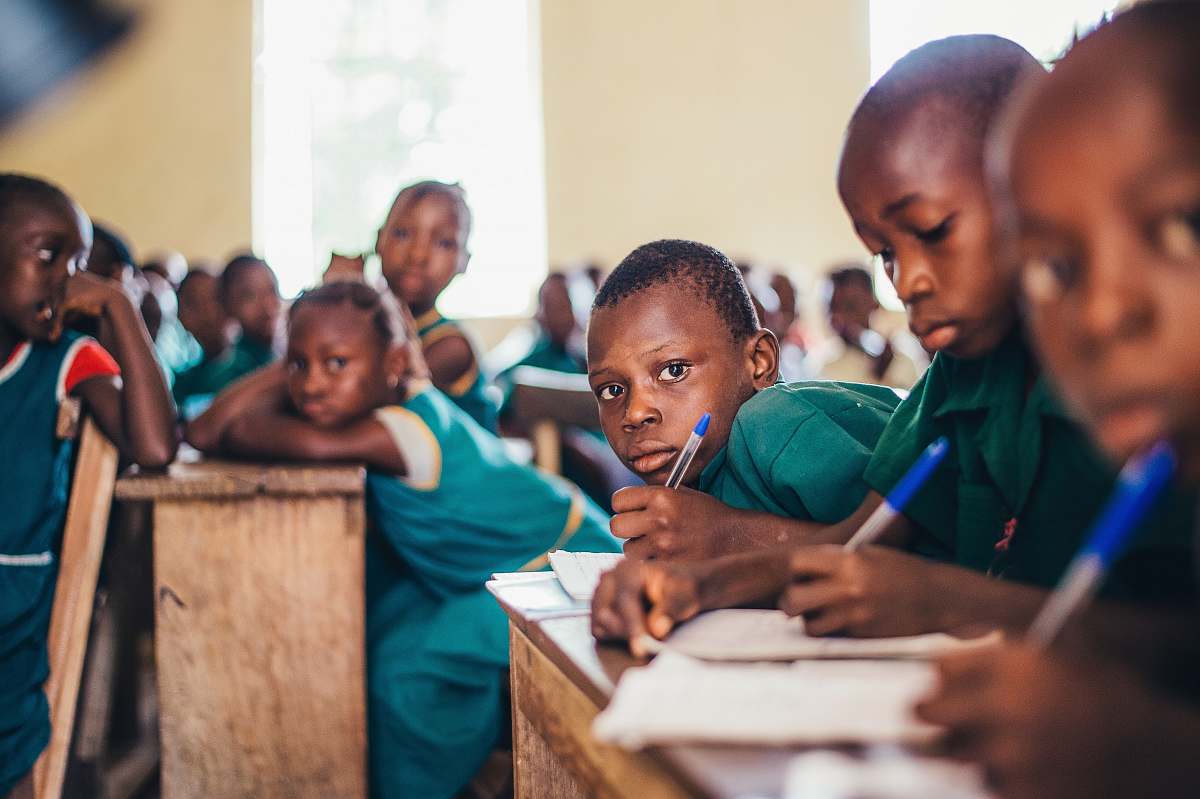 school children writing in books classroom