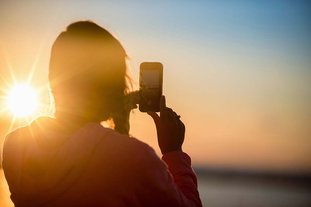 camera woman taking photo of sunset sun