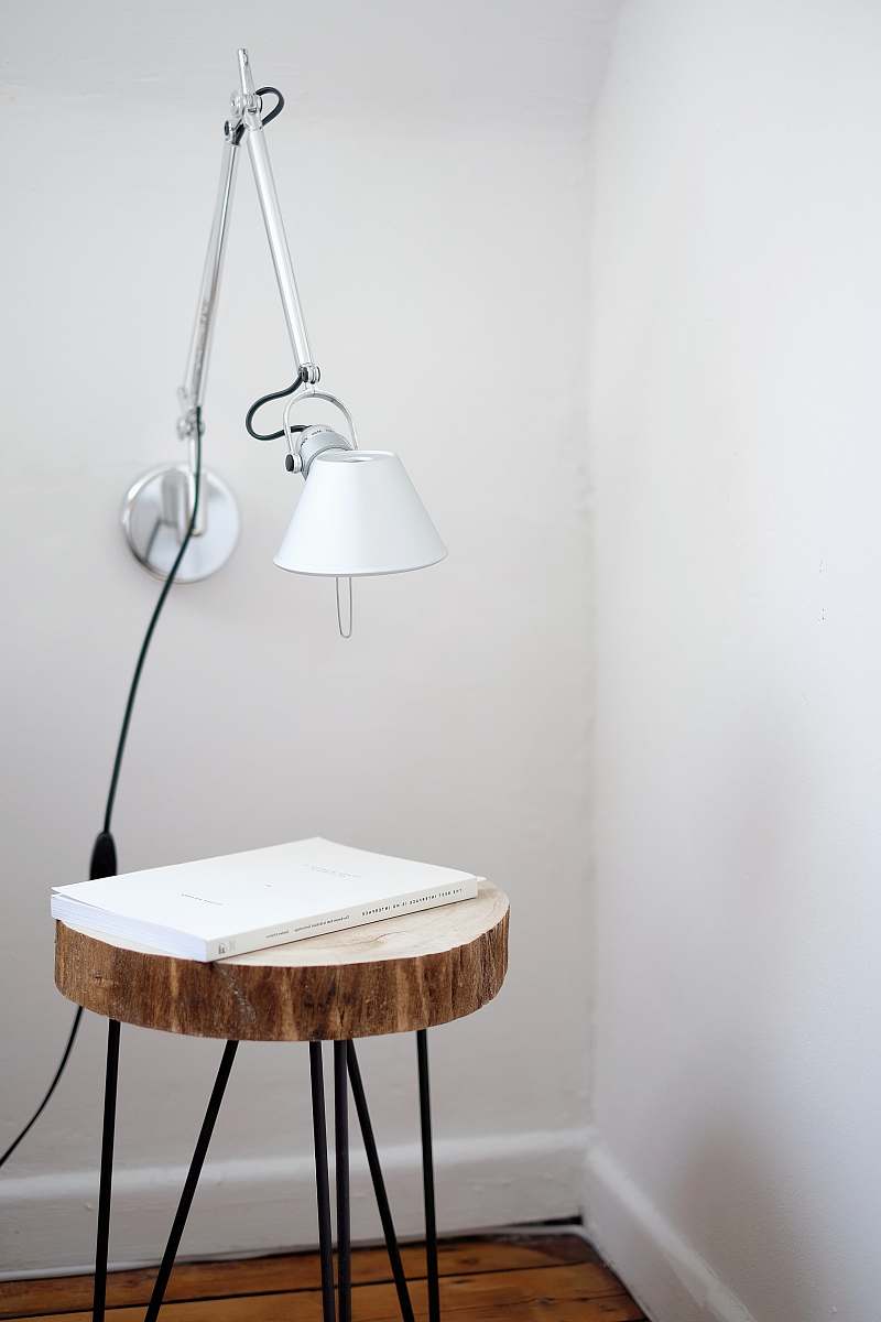 interior gray desk lamp mount on white wall under brown stool with white book on top near wall corner home