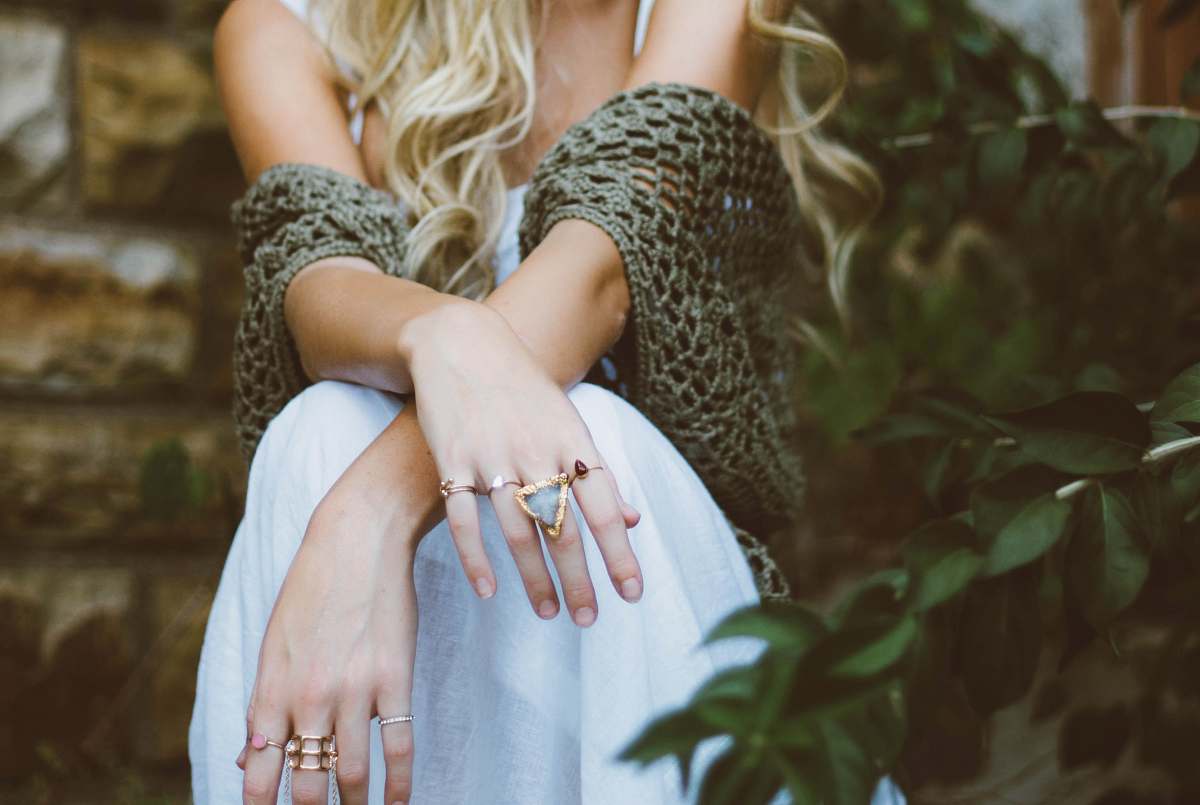 fashion woman sitting beside plant and concrete wall jewelry