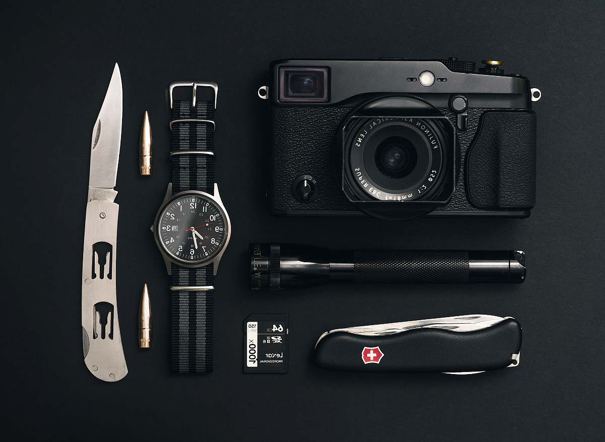 camera black camera, round silver-colored analog watch, black Swiss Gear pocketknife, and black flashlight electronics