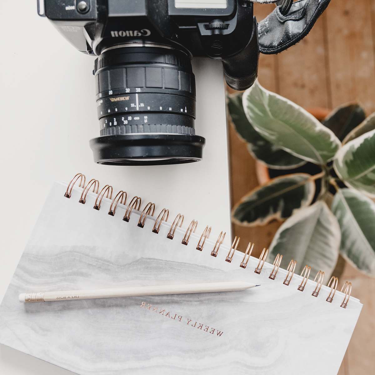 electronics black Canon DSLR camera on table beside notebook footwear