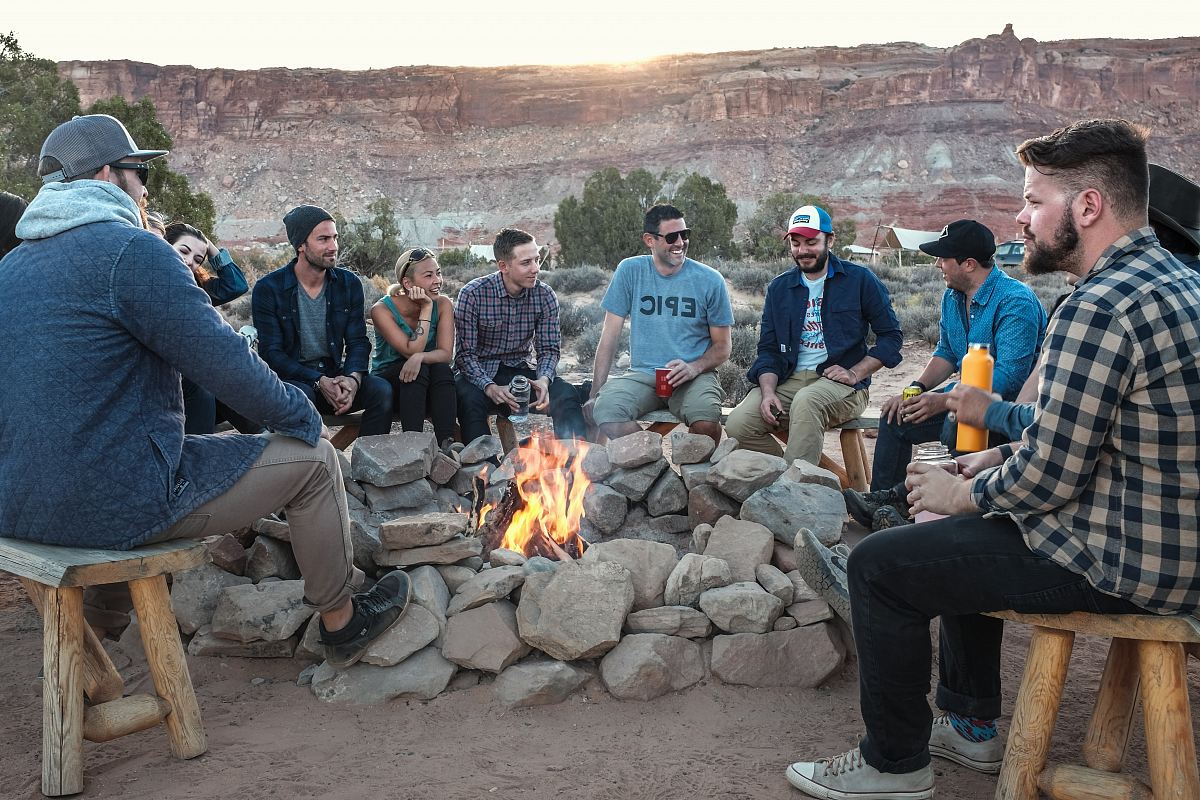 bonfire surrounded by group of people near brown hill during daytime