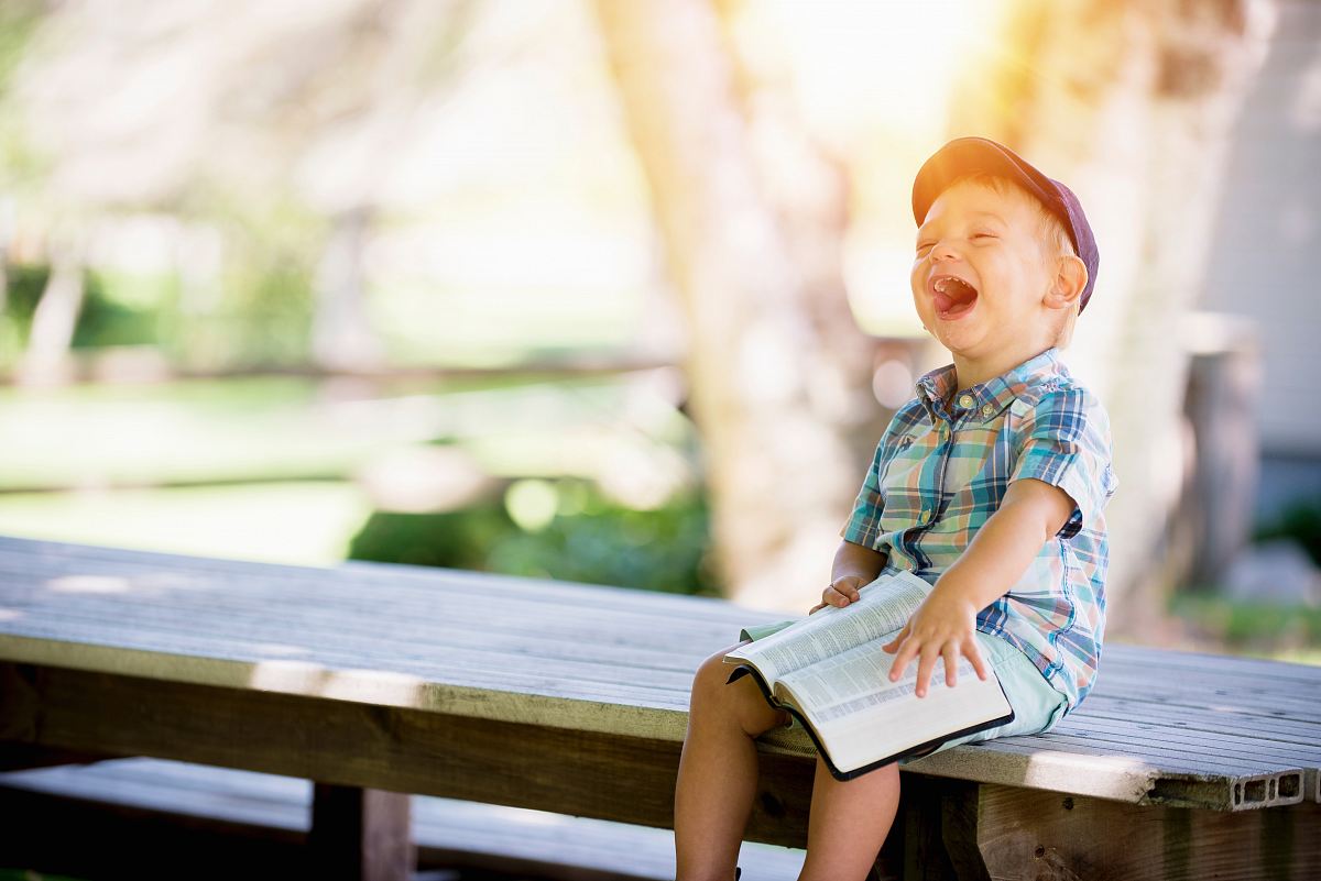 boy sitting on bench while holding a book