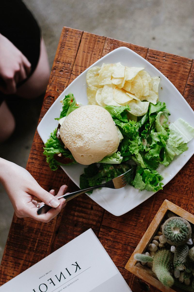 bun, lettuce, and chips served on white ceramic plate