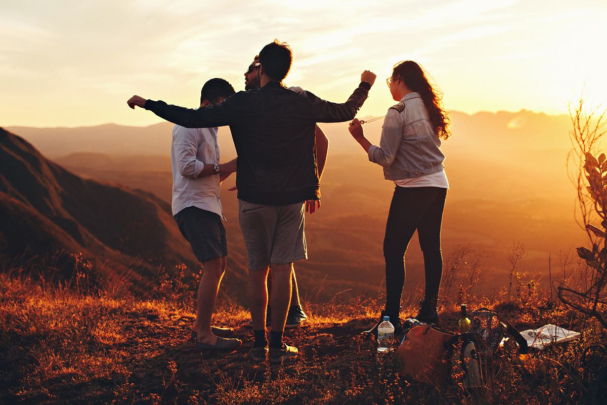 four people standing on edge of mountain