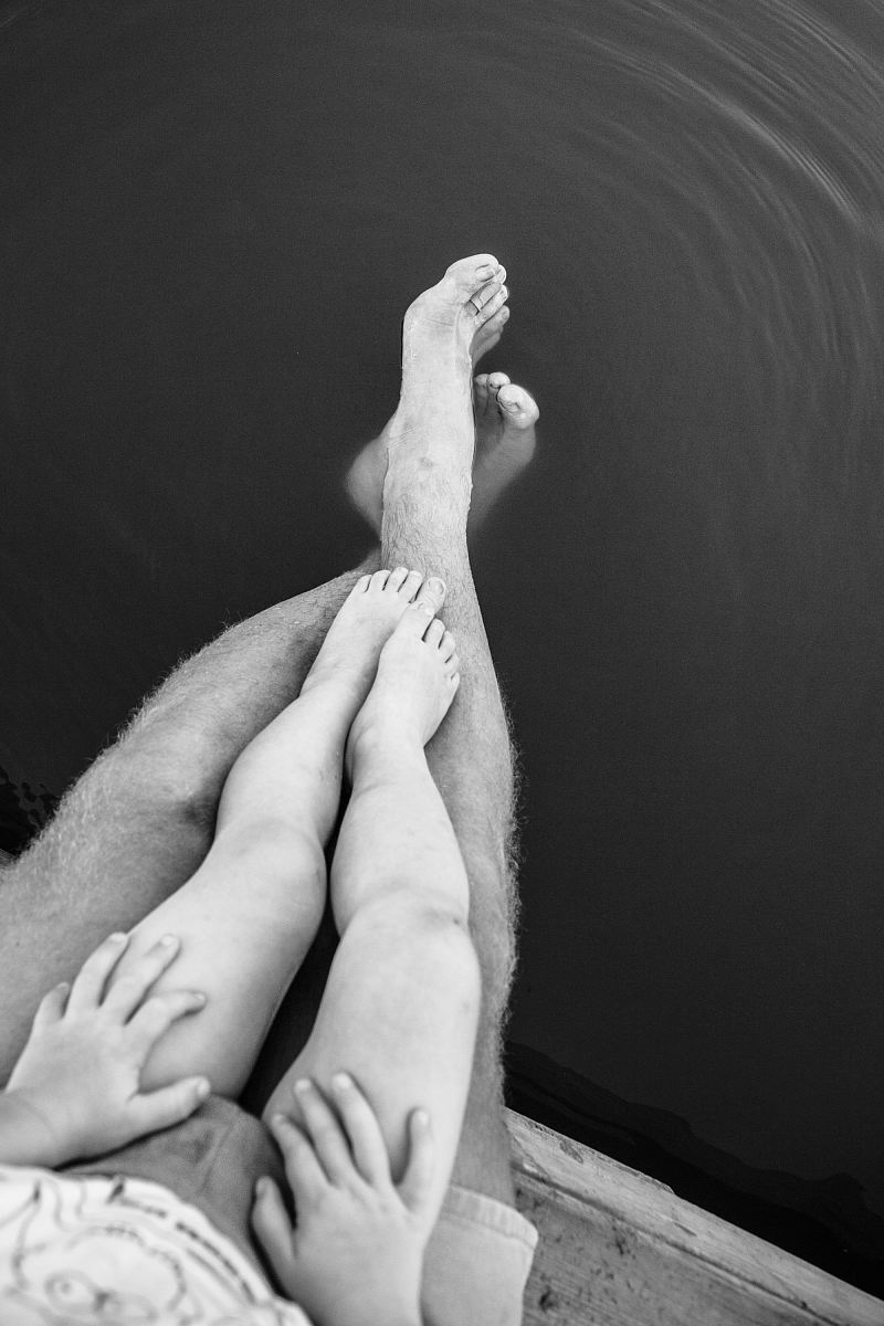 grayscale photo of person's feet on body of water