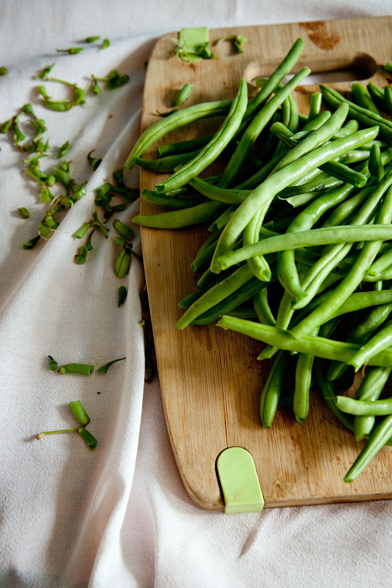 green peas on top of brown wooden chopping board