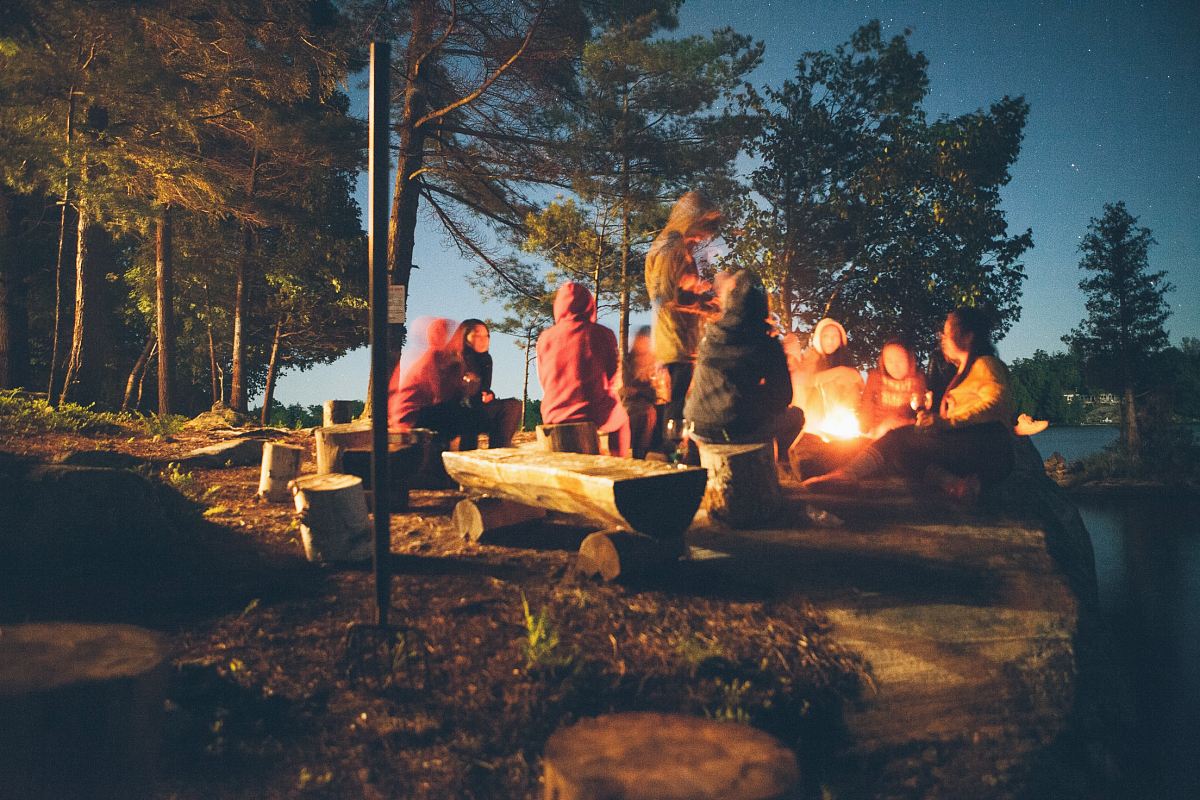 group of people near bonfire near trees during nighttime