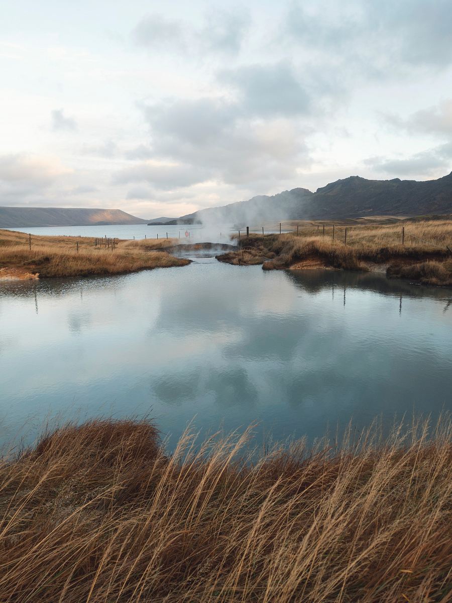 lake near mountain under cloudy sky at daytime