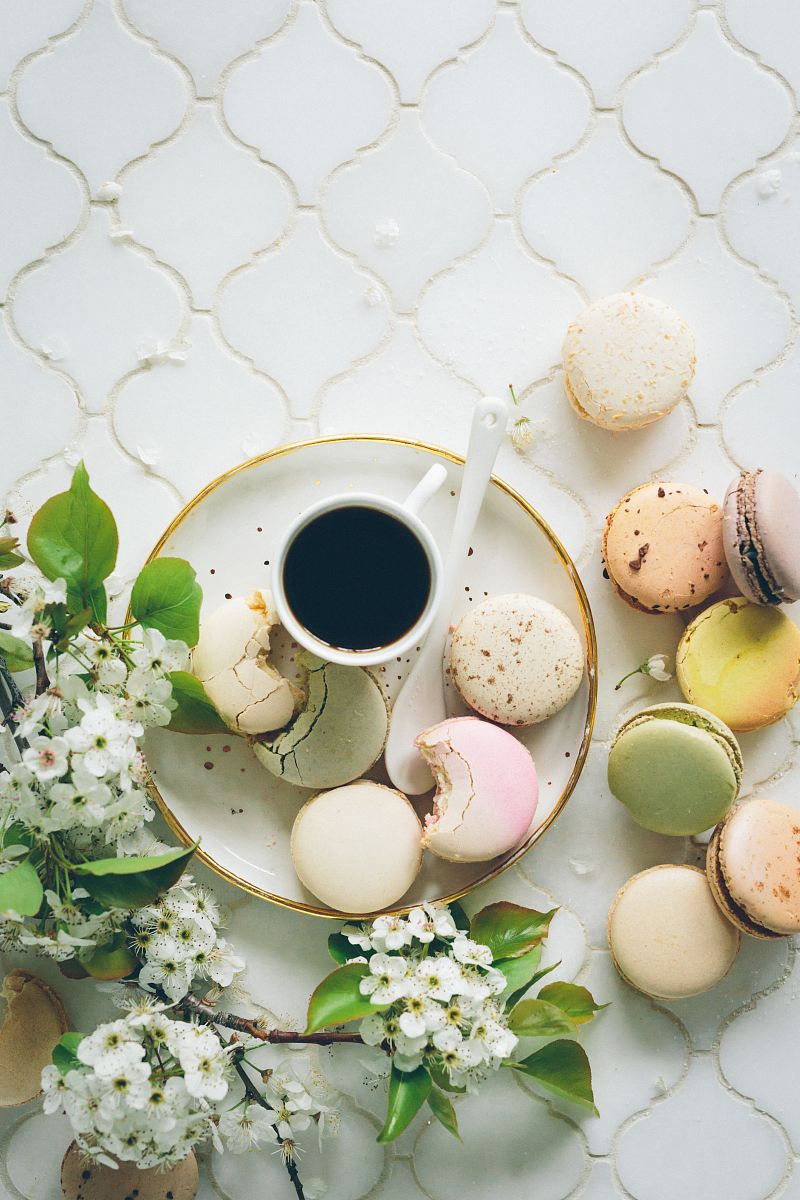 macarons beside teacup and ladle on round white ceramic plate