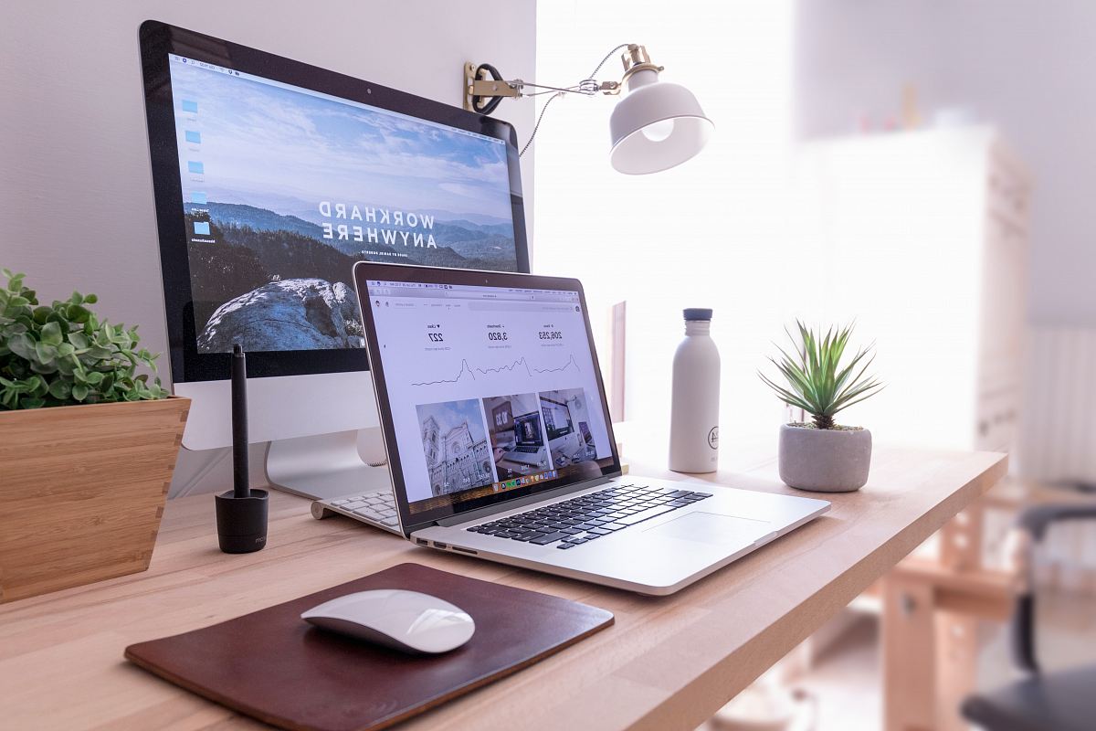 MacBook Pro on table beside white iMac and Magic Mouse