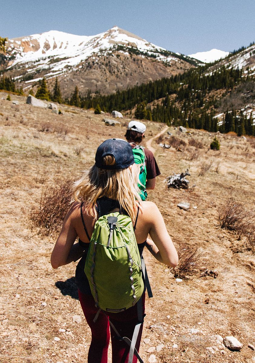 man and woman hiking on brown and white mountain
