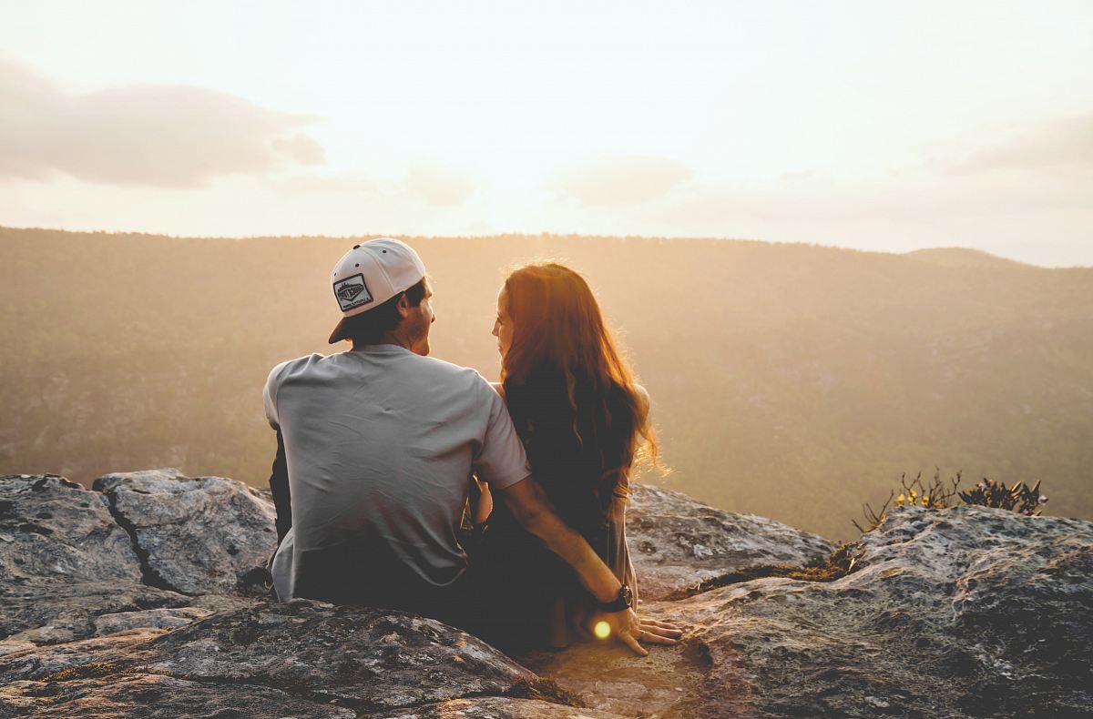 man and woman sitting on rock during daytime