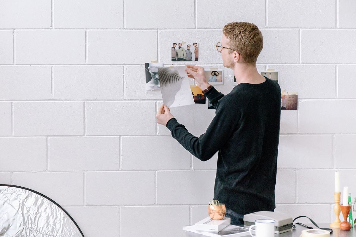 man holding paper infront by wall
